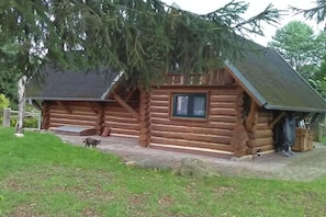 Eine Blockhütte mit Veranda, Fenster und Tür.