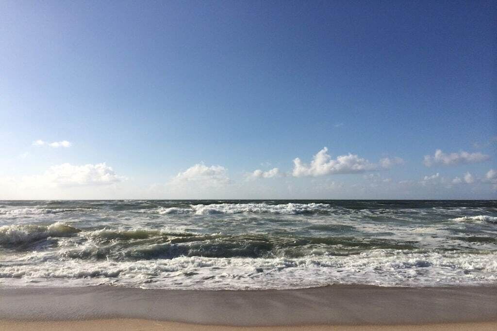 A beach with waves and a clear sky.