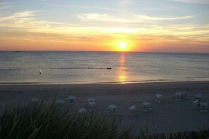 En strand med en solnedgång, ett lugnt hav och strandstolar.