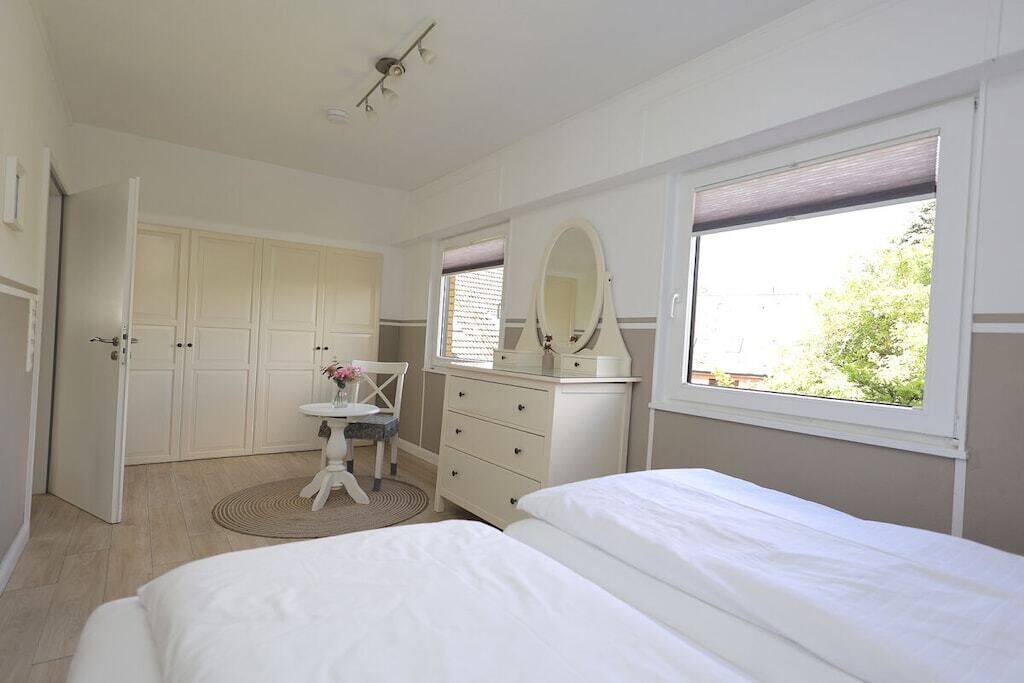 Ein Schlafzimmer mit einem Bett, einem Schminktisch, einem Spiegel und einem Fenster.