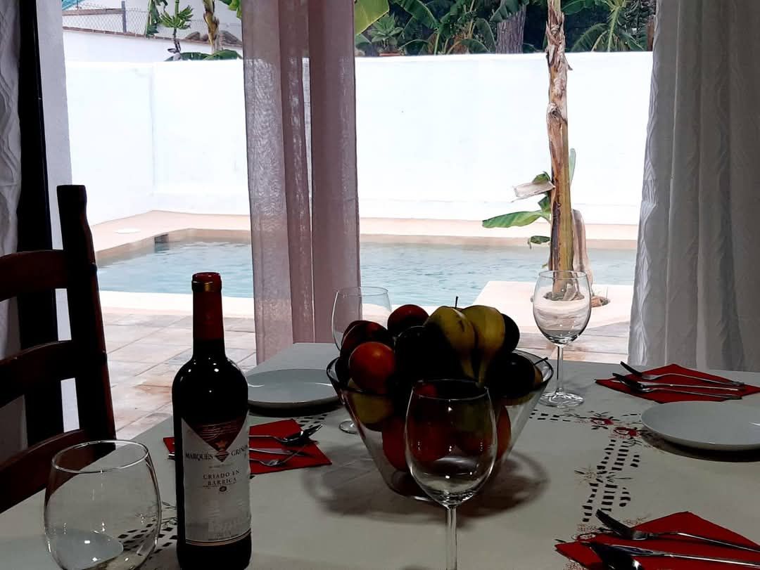 Een eettafel met een fles wijn, een glas en een schaal fruit.