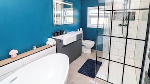 A modern bathroom with a bathtub, a toilet, and a glass-enclosed shower area. - Regents Cottage (Melton Mowbray)