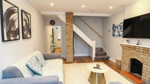 A living room with a sofa, a coffee table, a fireplace, and a TV mounted on the wall. - Regents Cottage (Melton Mowbray)
