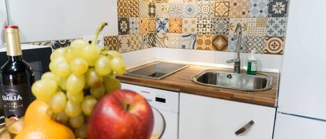 Una cocina con salpicadero de azulejos, un lavabo y un bol de fruta en la encimera.
