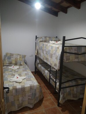 A bunk bed room with a quilted bedspread, a single bed with a pillow, and a headboard. - Villa Francesa     . (Chiclana de la Frontera)