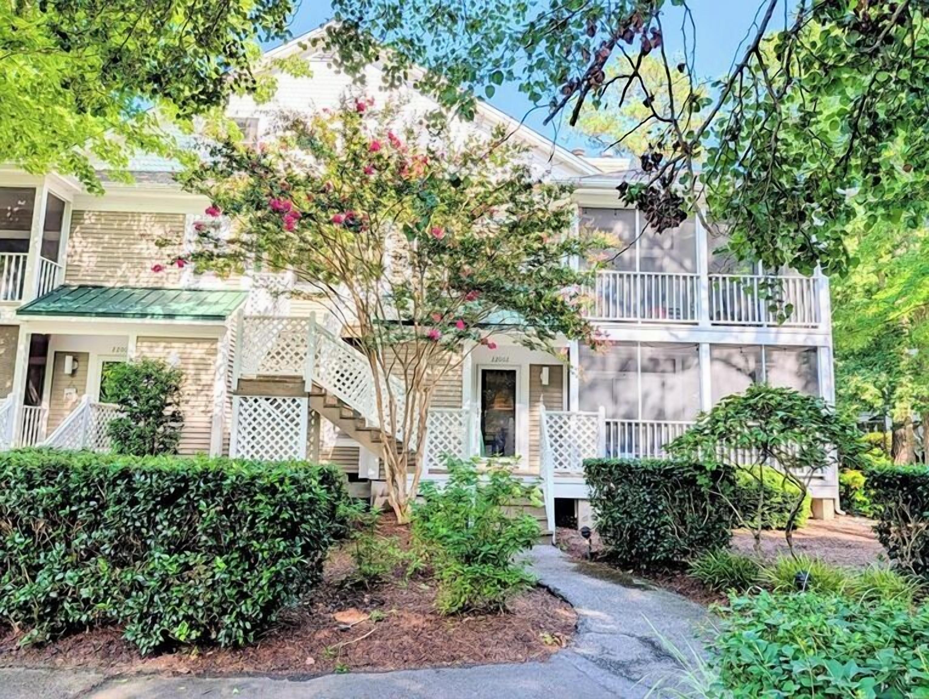 A two-story building with a balcony, a covered porch, and a small garden area. - Sea Colony 3BR Condo w/ Blue Screened Porch & Resort Amenities (Bethany Beach)