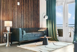 Ein Wohnzimmer mit einer Couch, einer Lampe, einem kleinen Tisch und Blick ins Freie.