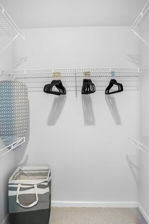 Ein begehbarer Kleiderschrank mit beschichtetem Kleiderbügel, einer Stauraumbank und einem Aufhängebeutel.