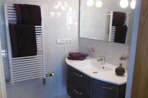 A bathroom with a white sink, dark cabinets, a mirror, and a towel rack with towels. - Arndt Holiday Apartment (Dresden Weißer Hirsch)