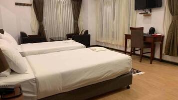 A hotel room with two beds, a desk, a chair, a TV, and curtains.