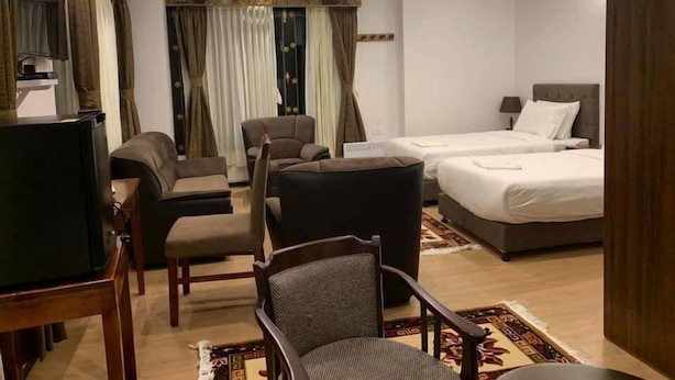 Una habitación de hotel con televisión, dos camas, un sofá y una silla.