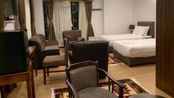 Una habitación de hotel con televisión, dos camas, un sofá y una silla.