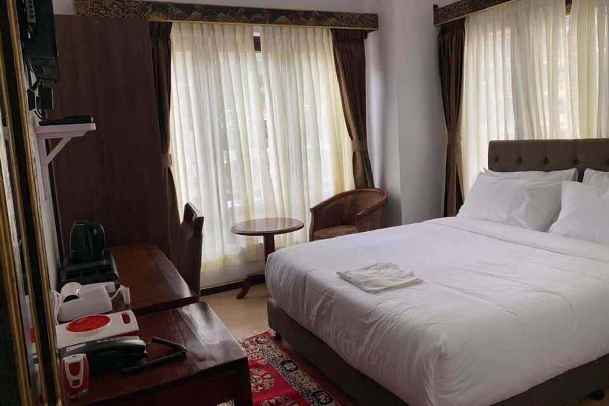 Une chambre d’hôtel comprenant un lit, un bureau avec un téléphone, une chaise et une petite table.