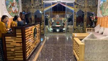 Un área de recepción con un mostrador de madera, un espacio de espera con sofá y un altar decorativo al fondo.