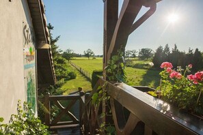 A wooden deck with a view of a green field and a clear sky. - Stein - Apartment Spreewald (Byhleguhre)