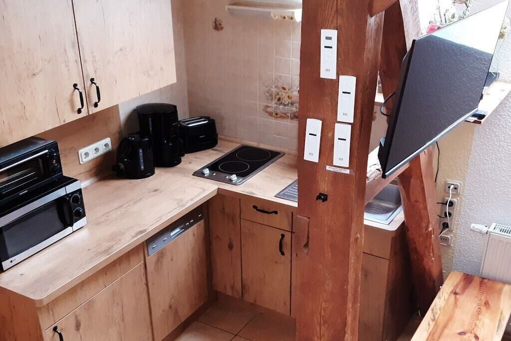 A compact kitchen with wooden cabinets, a built-in microwave, a coffee maker, and a stove.