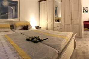 Ein Schlafzimmer mit einem Bett, einem Kleiderschrank, einem Spiegel und einem gerahmten Bild an der Wand.