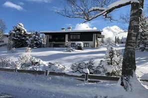 Ein modernes, zweistöckiges Haus mit verschneitem Einfahrt und umliegender Landschaft.