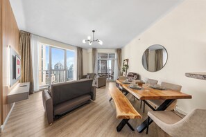En moderne stue med spiseplads, store vinduer og udsigt over bybilledet.