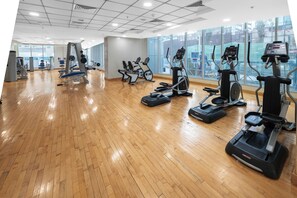 A gym with various exercise equipment, large windows, and a wooden floor. - StayShort - Stylish 2-Bedroom Escape in Dubai Marina for 4 guests! (Dubai Marina)