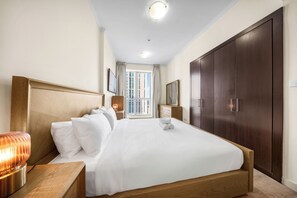 A hotel room with a large bed, a wardrobe, a bedside table with a lamp, and a window with curtains. - StayShort - Stylish 2-Bedroom Escape in Dubai Marina for 4 guests! (Dubai Marina)
