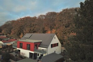 Ein modernes, zweistöckiges Haus mit rotem und weißem Anstrich, einem Balkon und einem geneigten Dach.