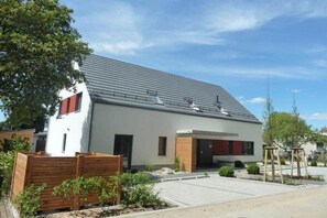 A modern two-story house with a flat roof, a small front porch, and a paved driveway. - 14° East Holiday Apartment 4 (Koserow)
