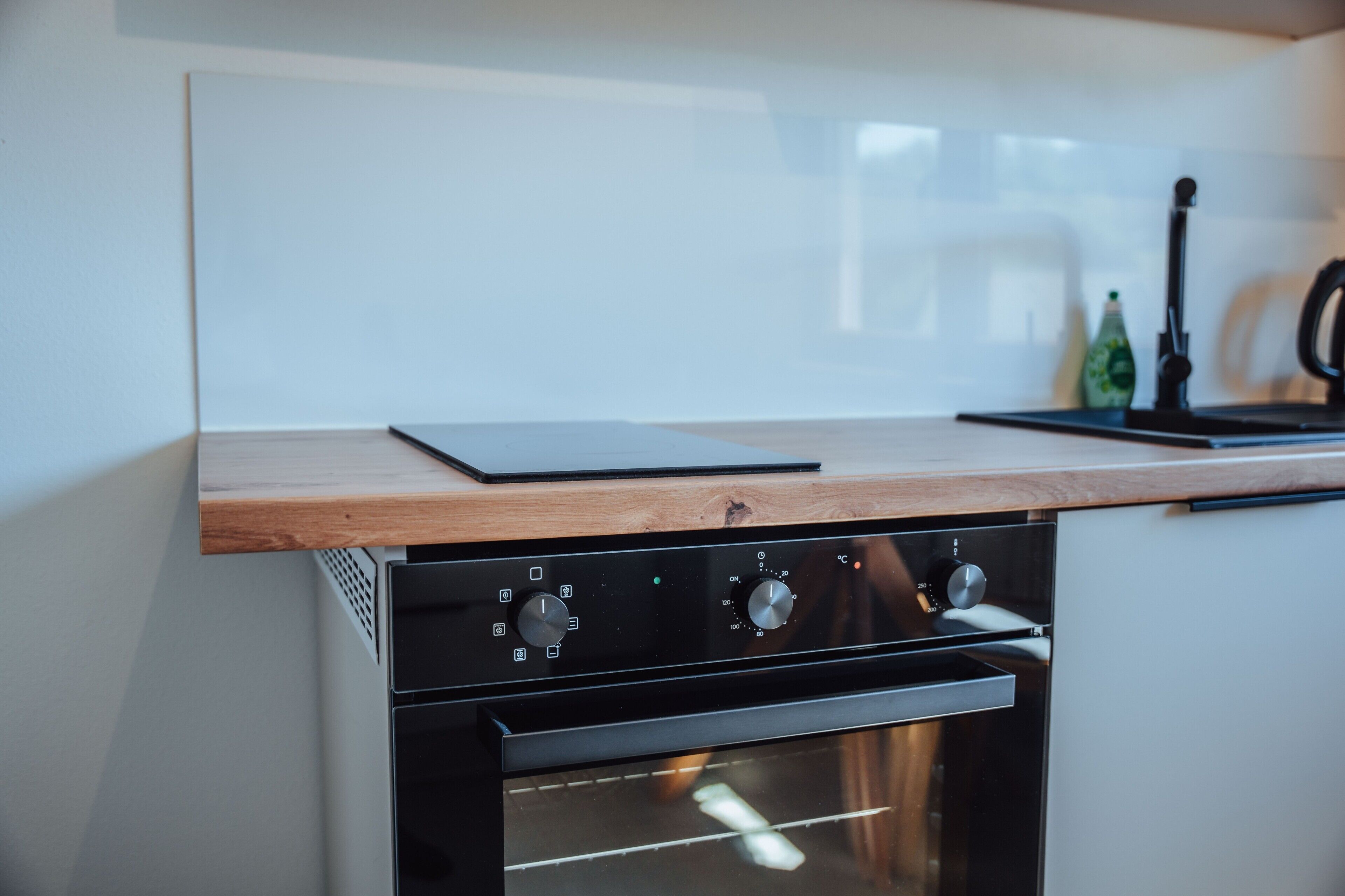 Una cucina con forno a incasso e piano di lavoro in legno.