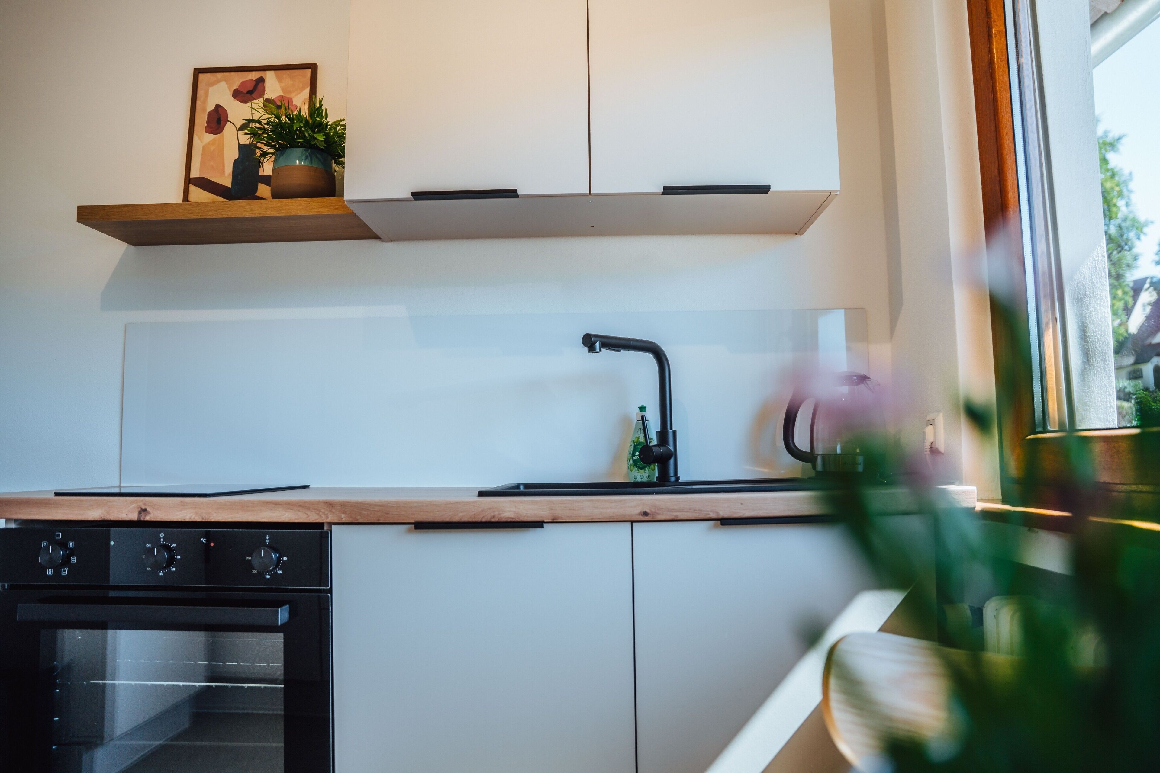 A modern kitchen with white cabinets, a black faucet, and a wooden countertop.