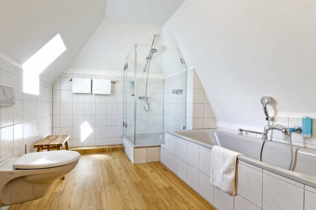 Ein modernes Badezimmer mit Oberlicht, Dusche, Toilette und Badewanne.
