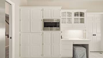 A kitchen with white cabinetry, a built-in microwave, and a countertop with a sink.