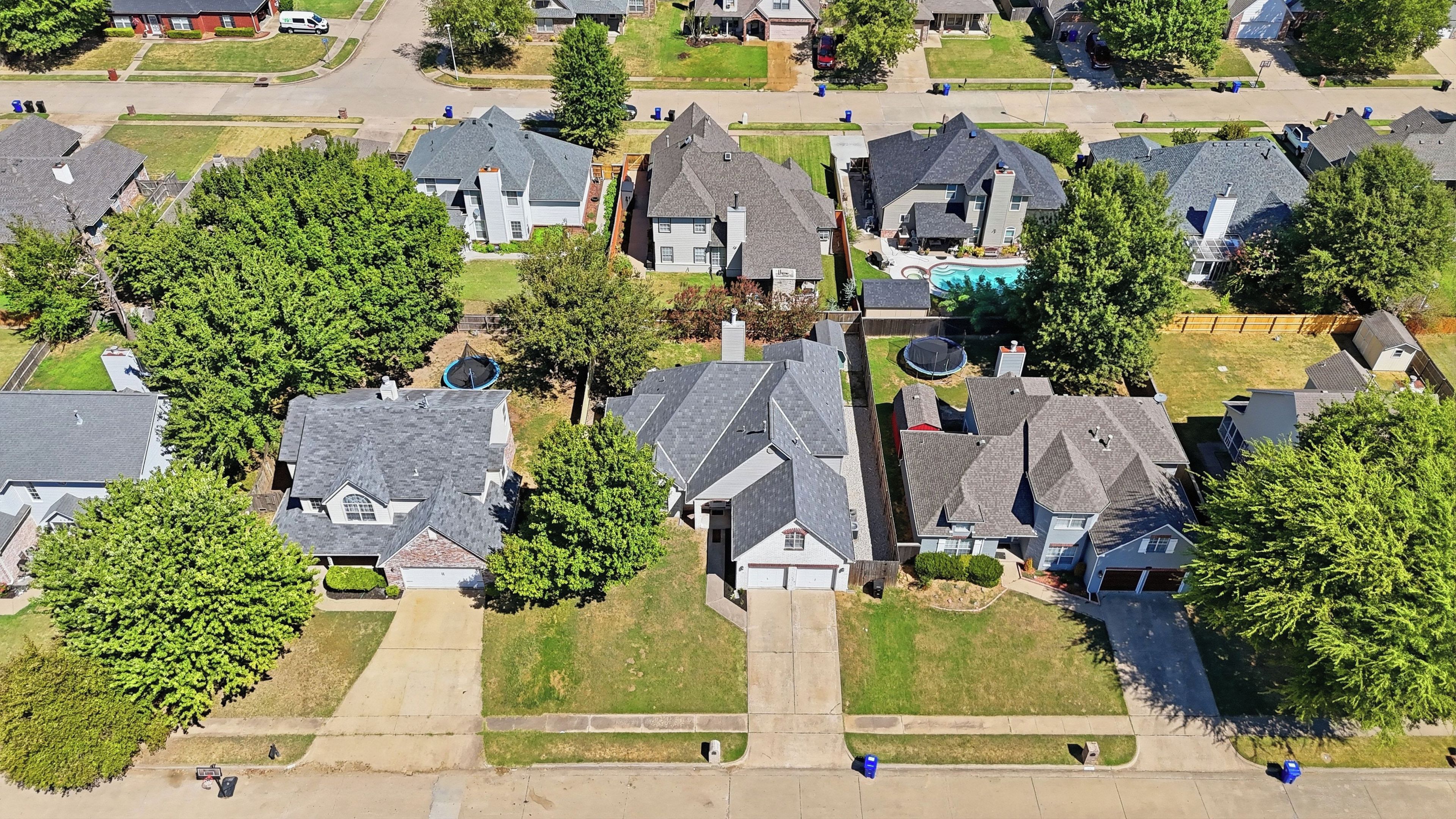 An aerial view of a residential area with houses, lawns, and a swimming pool.