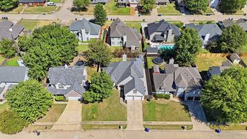 An aerial view of a residential area with houses, lawns, and a swimming pool.