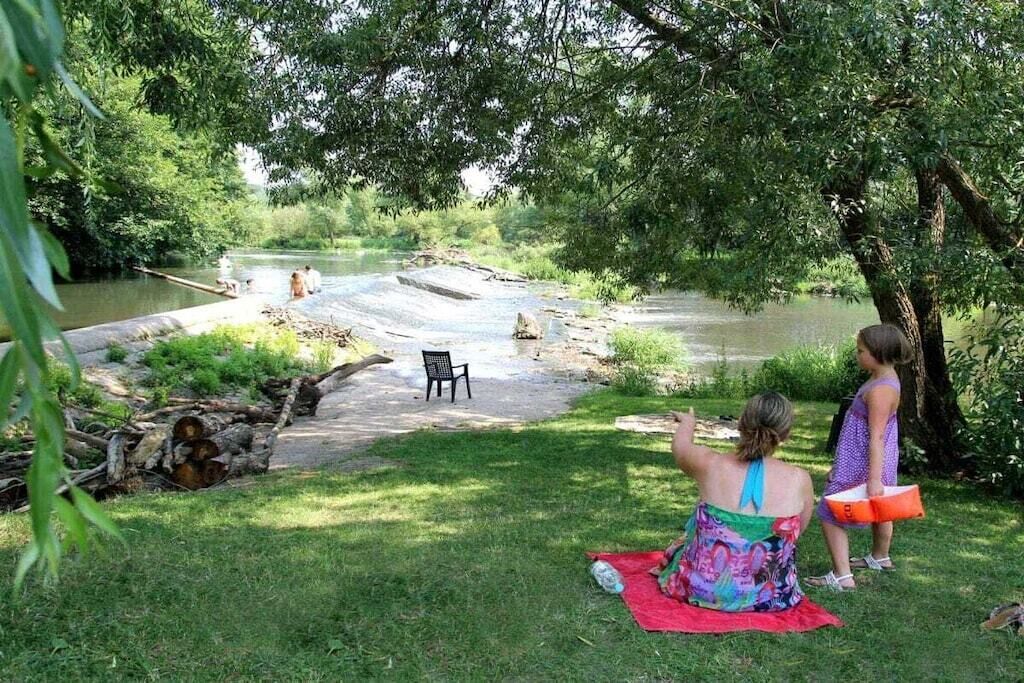 Un espace extérieur comprenant une rivière, une table de pique-nique et une chaise.