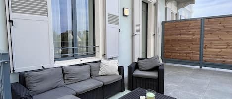 Terraza en la azotea con mobiliario exterior, incluyendo sofás y una mesa de centro, y una valla de madera.