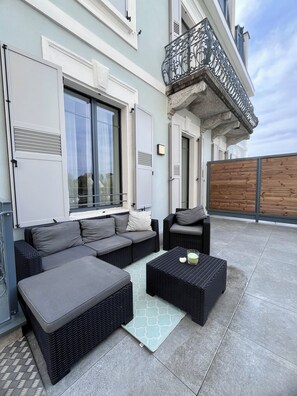 Eine Dachterrasse mit Außenmöbeln, darunter Sofas und ein Couchtisch, und einem Holzzaun.