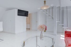 A modern interior with a glass coffee table, a red sofa, and a staircase. - Holiday apartment in Sylt with 1 bedroom (Wenningstedt)
