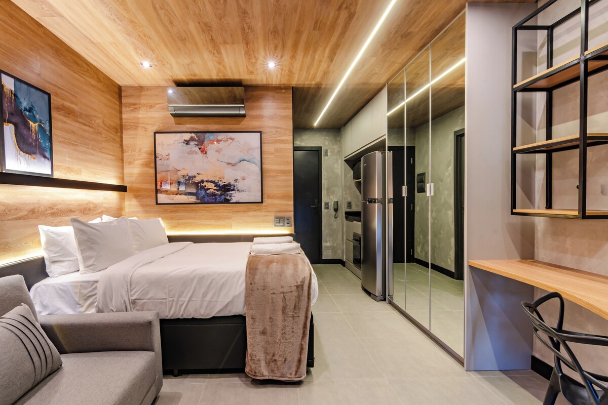 Una camera da letto moderna con un letto, un divano, una scrivania e un grande quadro astratto appeso al muro.
