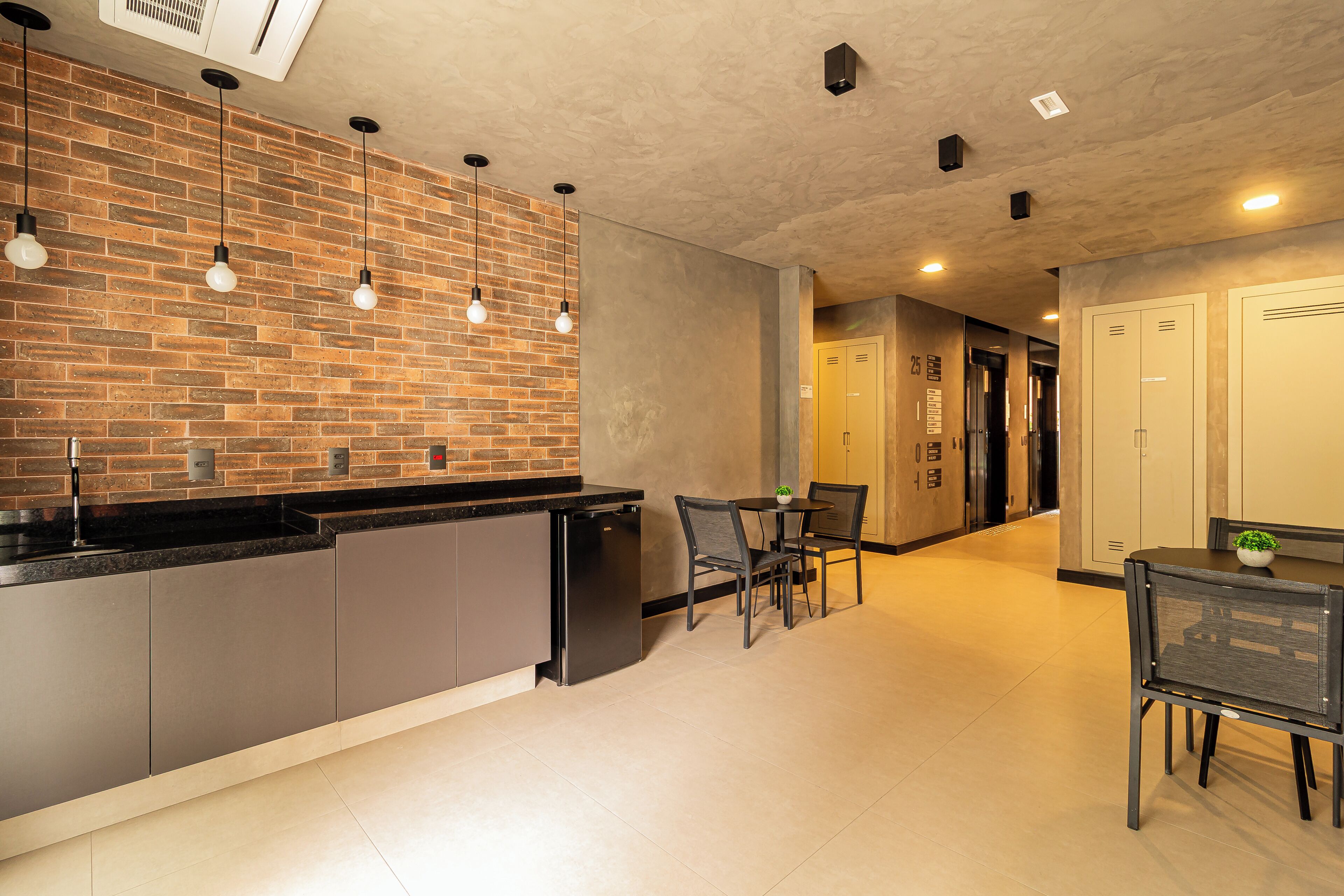 A modern kitchen with a brick backsplash, a dining area with two chairs, and a small table.