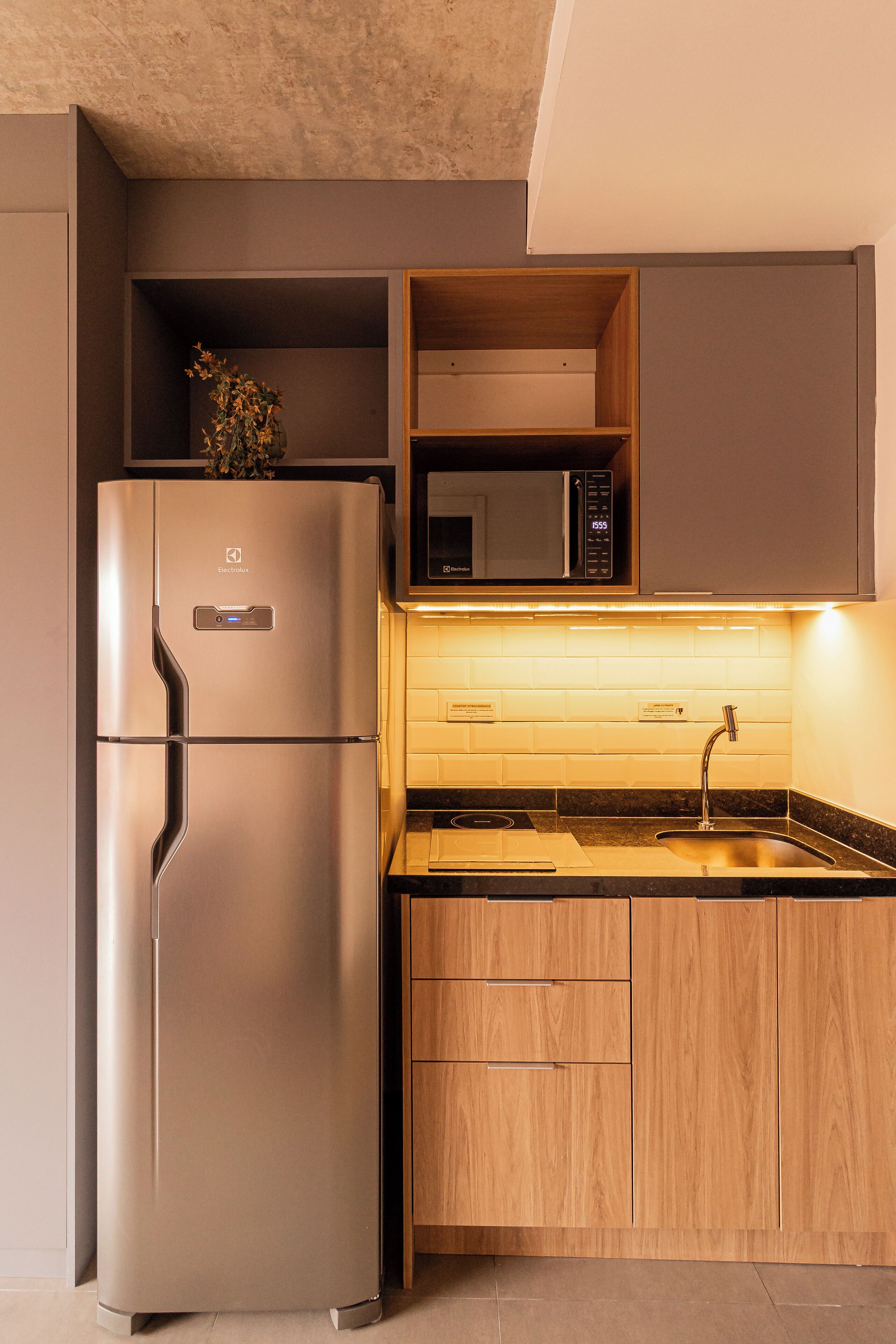 Une cuisine compacte équipée d’un réfrigérateur en acier inoxydable, d’un four à micro-ondes et d’un évier avec un plan de travail en bois.