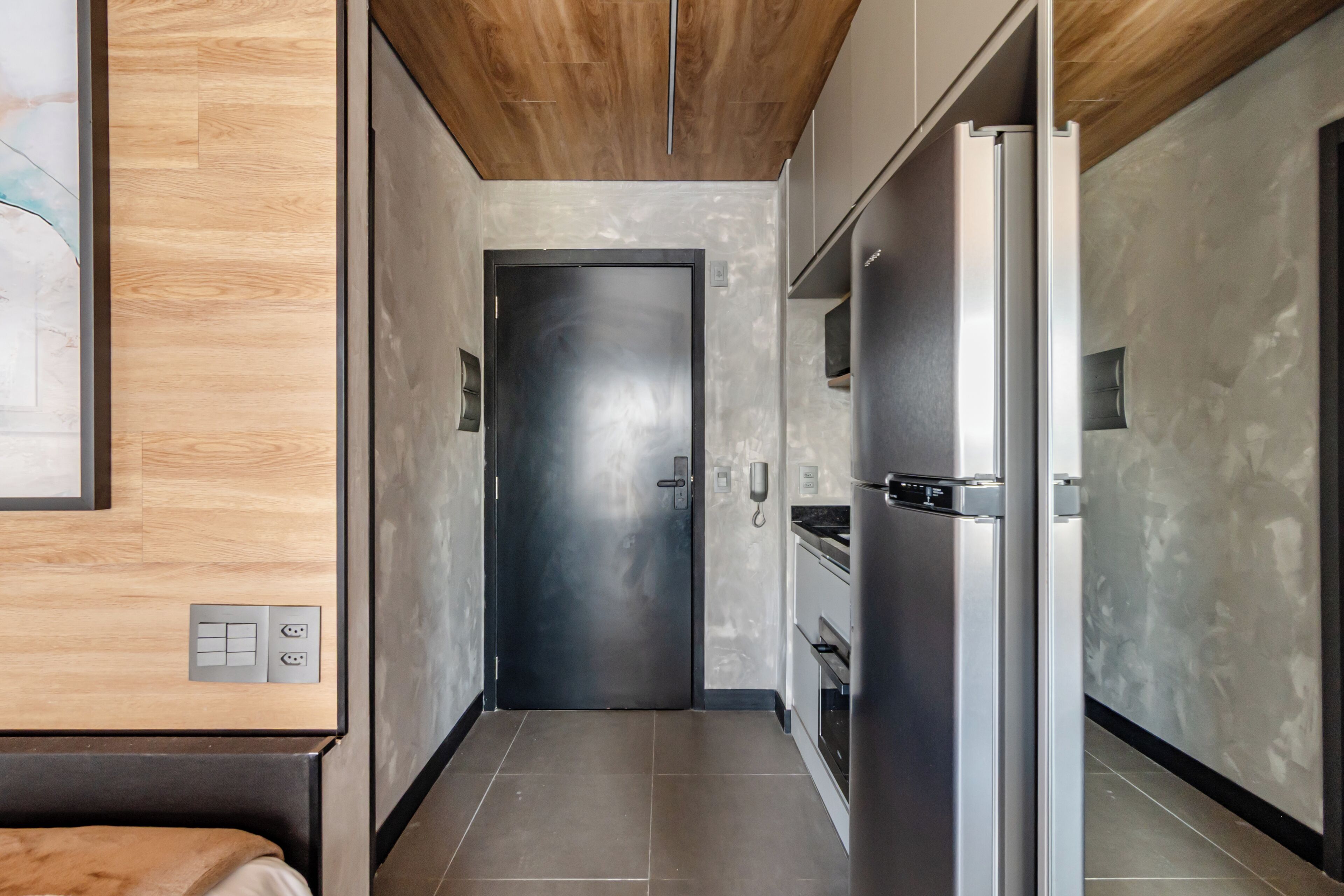 A modern kitchen with stainless steel appliances, a wooden ceiling, and a tiled floor.