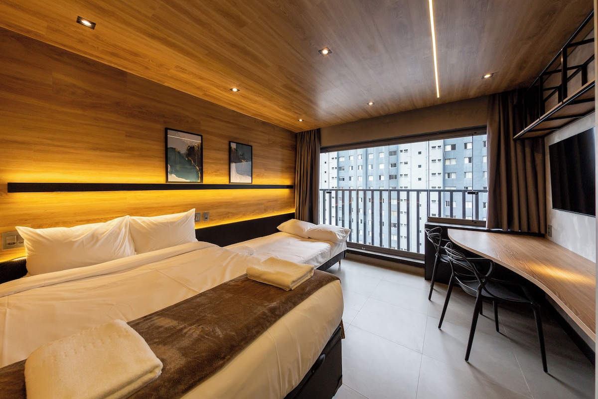 Una camera d'albergo con un letto, una scrivania e vista su un edificio dalla finestra.