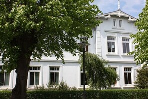 A white building with multiple windows and a central entrance. - Holiday apartment Strandstraße 16 322221 (Kühlungsborn)