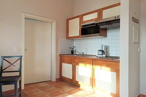 A kitchen with wooden cabinets, a built-in oven, and a coffee maker. - Holiday apartment Strandstraße 16 322221 (Kühlungsborn)
