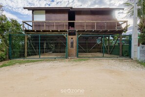 Un edificio in legno a due piani con un balcone, un ingresso chiuso da cancello e una targa.