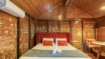 A wooden room with a bed, a red upholstered headboard, and floral wall decorations.