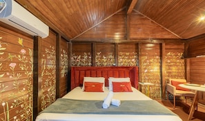 Una camera in legno con un letto, una testiera imbottita rossa e decorazioni floreali alle pareti.