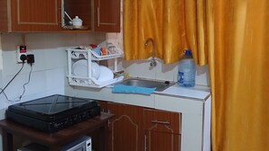 A compact kitchen with a microwave, a kettle, a sink, and a water dispenser. - Studio airbnb mirema drive (Nairobi)