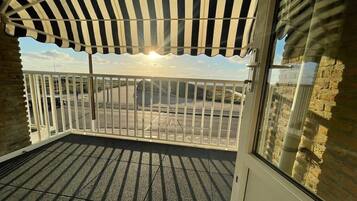A balcony with a view of a parking lot and a building in the distance.