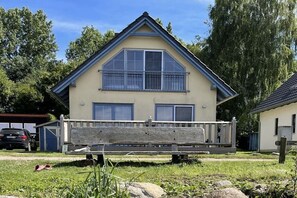 Ein zweistöckiges Haus mit einem Balkon, einem Holzzaun und einem geparkten Auto im Hintergrund.